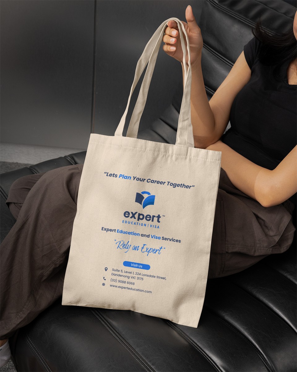 A person holding a cream Expert Education tote bag